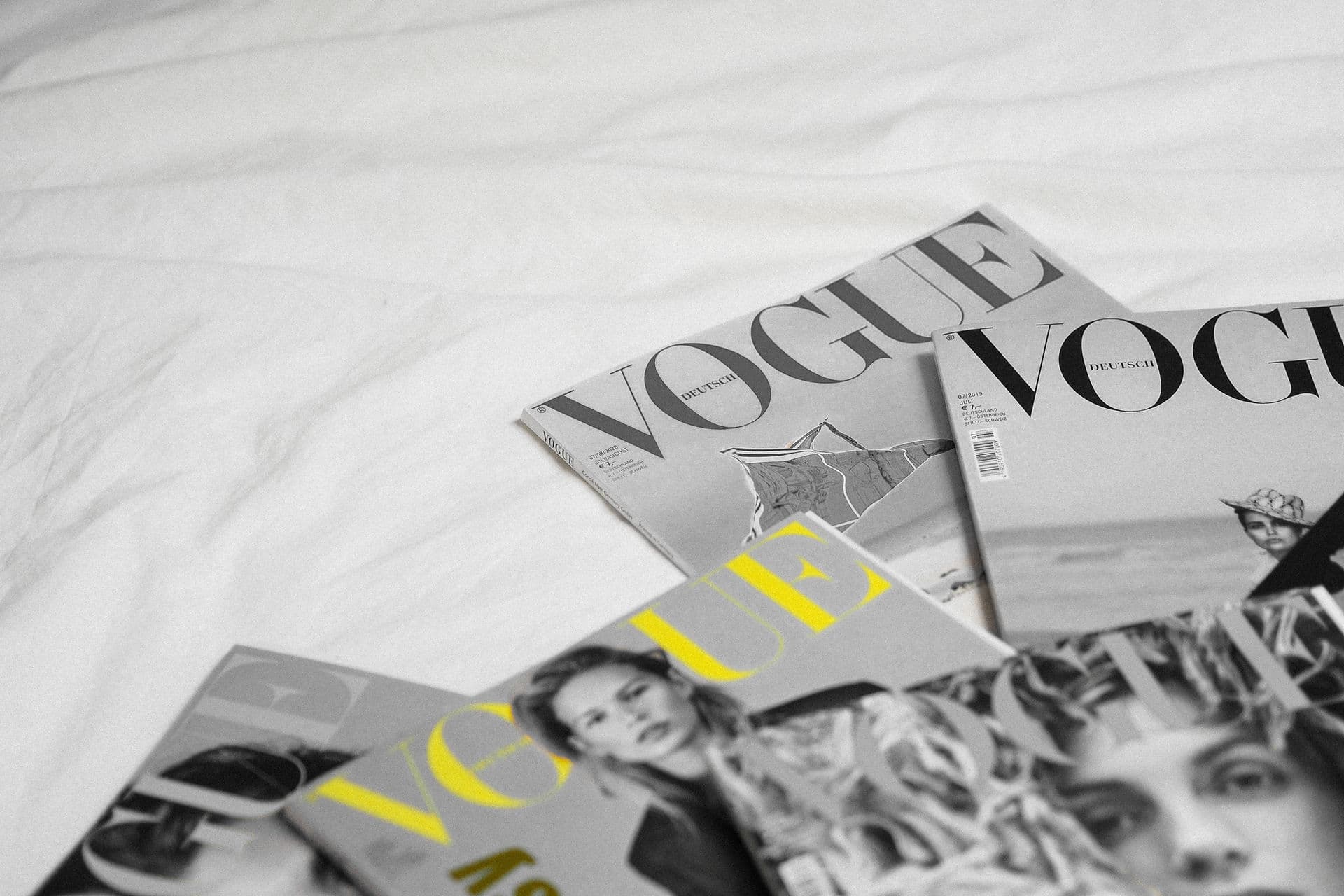 Vogue magazines spread on white linen — editorial brand styling